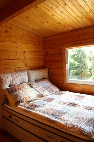 a bed in a log cabin with a window at Koło Żółwia in Gąski