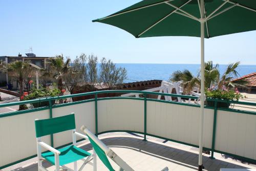 two chairs and an umbrella on a balcony with the ocean at Lungomare Hotel in Marina di Cecina