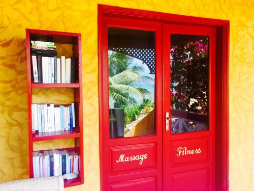 a red door with two shelves of books at Maison Couleur Passion in Nianing