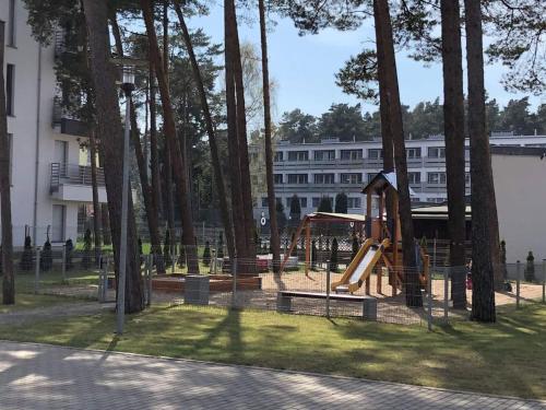 a playground with a slide in a park with trees at Apartment LILY - Baltic Park Pogorzelica in Pogorzelica