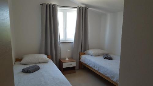 two beds in a small room with a window at Apartmani Vrdoljak Malinska in Malinska