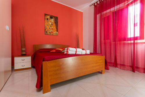 a bedroom with red walls and a bed with a wooden bench at Rifugio Delle Nereidi in Marina di Mancaversa