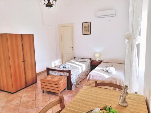 カストロ・ディ・レッチェにあるCentro Storico di Castro Marinaのベッドルーム1室(ベッド2台、テーブル、椅子付)