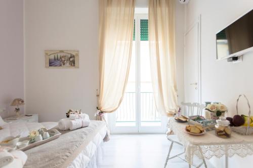 ein weißes Zimmer mit einem Bett und einem Tisch in der Unterkunft La Maison Romantique in Neapel