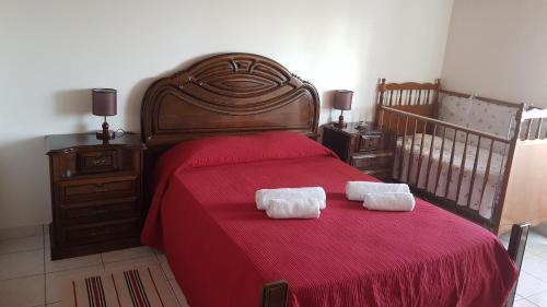 1 dormitorio con 1 cama roja y 2 toallas en Adega do Batista en Calheta