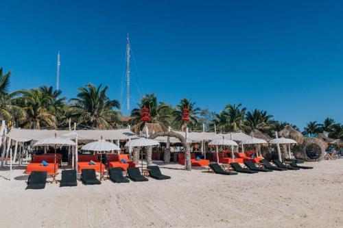 a group of chairs and umbrellas on a beach at Serenity Authentic Glamping Tulum in Xpu Ha