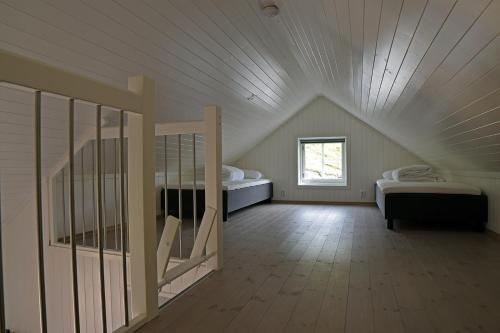a attic room with two beds and a window at Lofoten Cabins - Kåkern in Ramberg