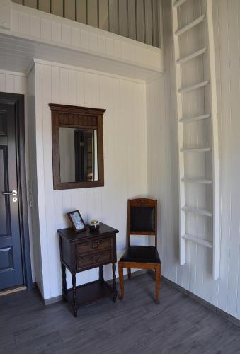 a room with a chair and a table and a mirror at Lofoten Cabins - Kåkern in Ramberg