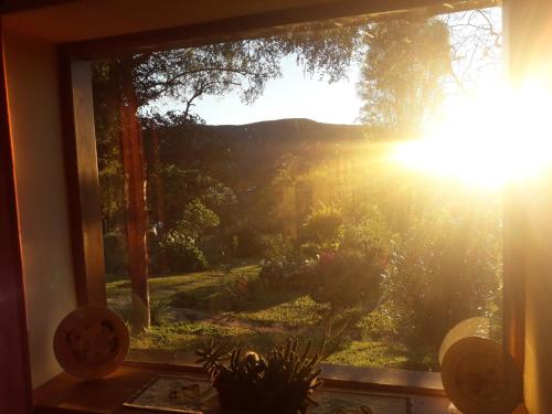 a window with a view of the sun shining through at Hostel Serena in Samaipata