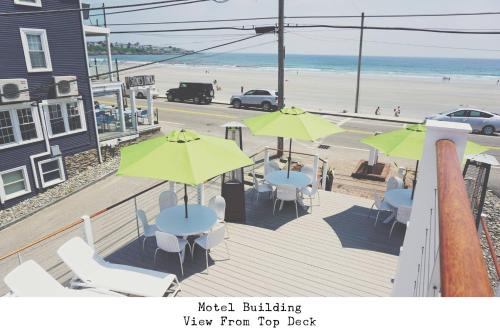 a deck with tables and umbrellas and a beach at Stones Throw in York Beach
