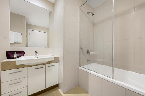 a white bathroom with a sink and a shower at Quest Moorabbin in Moorabbin
