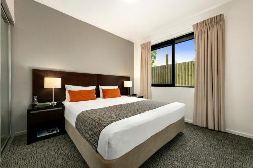 a bedroom with a large bed and a large window at Quest Moorabbin in Moorabbin