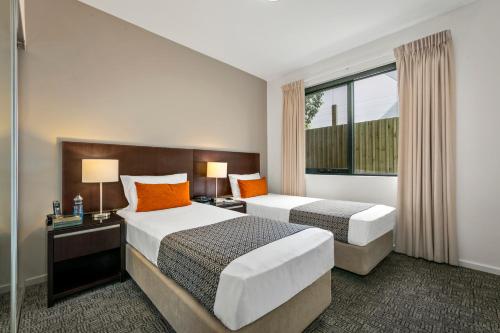 a hotel room with two beds and two lamps at Quest Moorabbin in Moorabbin