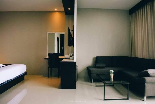 a bedroom with a bed and a couch and a table at The Harbour Front Hotel in Suratthani
