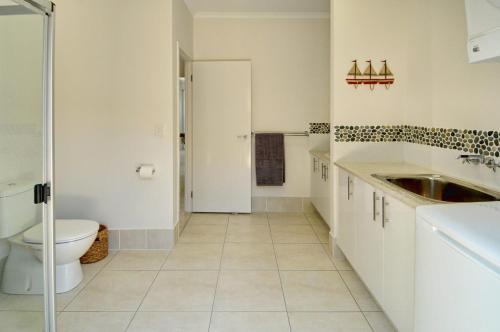 a white bathroom with a toilet and a sink at Coolum Street 41 Dicky Beach in Caloundra