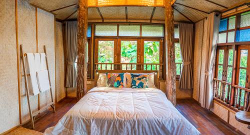 a bedroom with a bed in a room with windows at baanchandra in Chiang Mai
