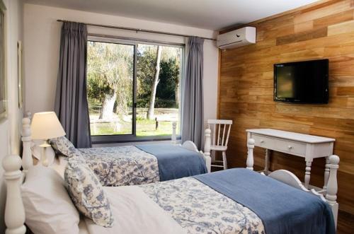 a bedroom with two beds and a desk and a window at María Cristina Posada in Punta del Este