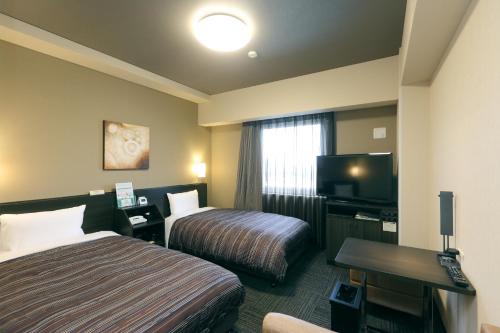 a hotel room with two beds and a flat screen tv at Hotel Route-Inn Shimizu Inter in Shizuoka