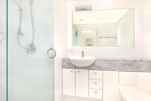 a white bathroom with a sink and a mirror at Spinnaker Quays in Mooloolaba