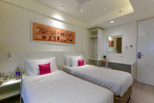 two beds in a hotel room with pink pillows at Hotel Centro in Pune