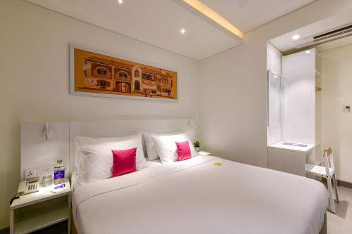 a bedroom with a large white bed with pink pillows at Hotel Centro in Pune