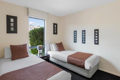 羅托魯阿的住宿－羅托魯瓦馬拉馬華美達度假村，酒店客房设有两张床和窗户。