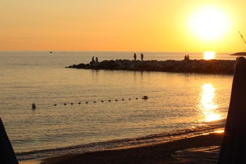a group of people on the beach at sunset at Lungomare Hotel in Marina di Cecina
