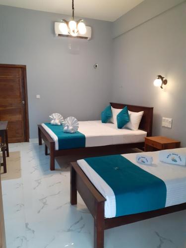 two beds in a room with blue and white at MRD Beach Hotel in Trincomalee