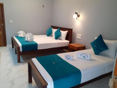 two beds in a room with blue and white at MRD Beach Hotel in Trincomalee