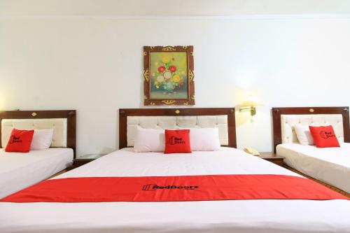 a bedroom with two beds with red pillows on them at RedDoorz at Hotel Putra Perdana Klaten in Klaten