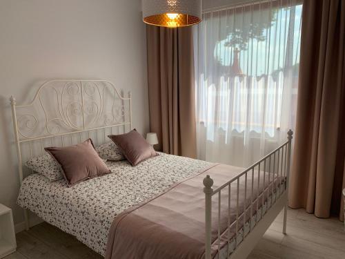 a bedroom with a white bed and a window at Apartament Zacisze Rose Gold in Malbork