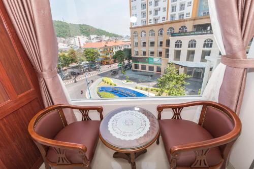 a table and two chairs in front of a window at Kyo Hotel in Vung Tau