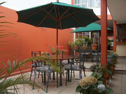 a patio with tables and chairs with an umbrella at Hotel Camba in Oaxaca City