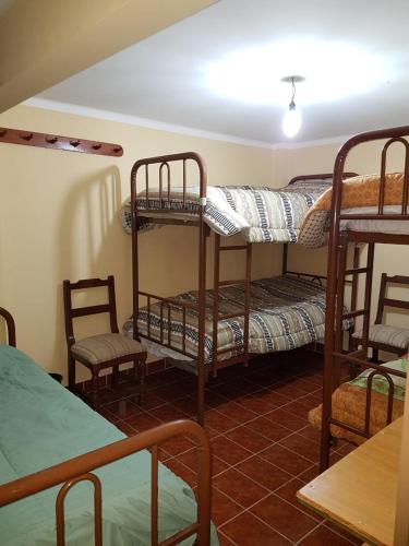 a room with three bunk beds and a table and chairs at Hostel Buen descanso in Sucre
