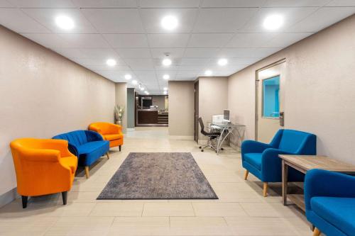 an office lobby with orange chairs and a table at Sleep Inn Terre Haute University Area in Terre Haute