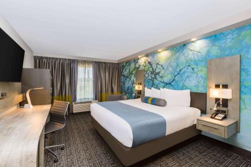 a hotel room with a large bed and a mural at Wingate by Wyndham Goodlettsville in Goodlettsville