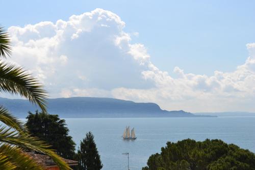 a sail boat in the water with a cloud formation at Hotel Villa Florida & Suite Apartments in Gardone Riviera
