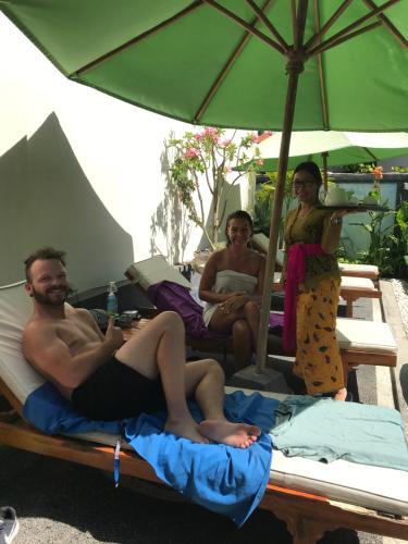 a group of people sitting on beds under an umbrella at Puri Clinton Bali in Nusa Dua