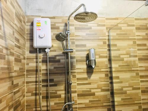 a shower with a shower head on a wooden wall at SP Home BangSaen in Bangsaen