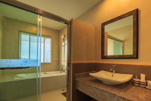 a bathroom with a sink and a mirror and a tub at Kwan Ruen Park in Nakhon Ratchasima