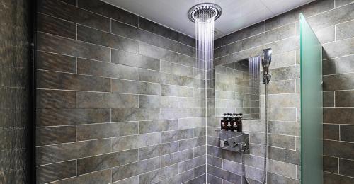 y baño con ducha y pared de azulejos. en Hotel Mondavi en Mokpo