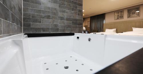 a bath tub in a room with two beds at Hotel Mondavi in Mokpo