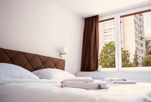 Schlafzimmer mit einem Bett mit weißer Bettwäsche und einem Fenster in der Unterkunft Hotel Slavija Banja Luka in Banja Luka