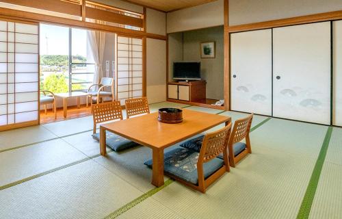 a living room with a wooden table and chairs at Awara Kitagata Onsen Kohanso Hana Yurari in Awara