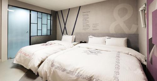 two beds in a room with white sheets at Hotel Mondavi in Mokpo
