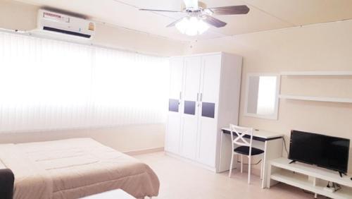 una camera da letto con un letto, una scrivania e una televisione di Popular Condo C8 a Nonthaburi