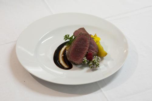 une plaque blanche avec un morceau de viande et de légumes dans l'établissement Albergo Morandi, à Valbondione