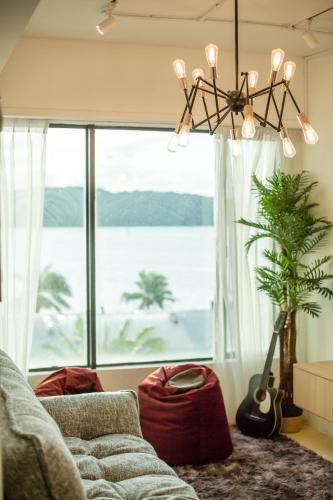コタキナバルにあるHomy Seafront Hostelのソファと大きな窓のあるリビングルーム