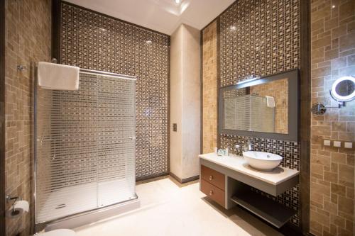 a bathroom with a sink and a shower with a mirror at Saat Meydani Nakhchivan in Naxçıvan