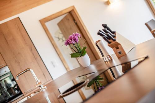 a kitchen counter with a table with a vase of flowers on it at GOTTHARD - FINE LIVING APARTMENTS in Seefeld in Tirol